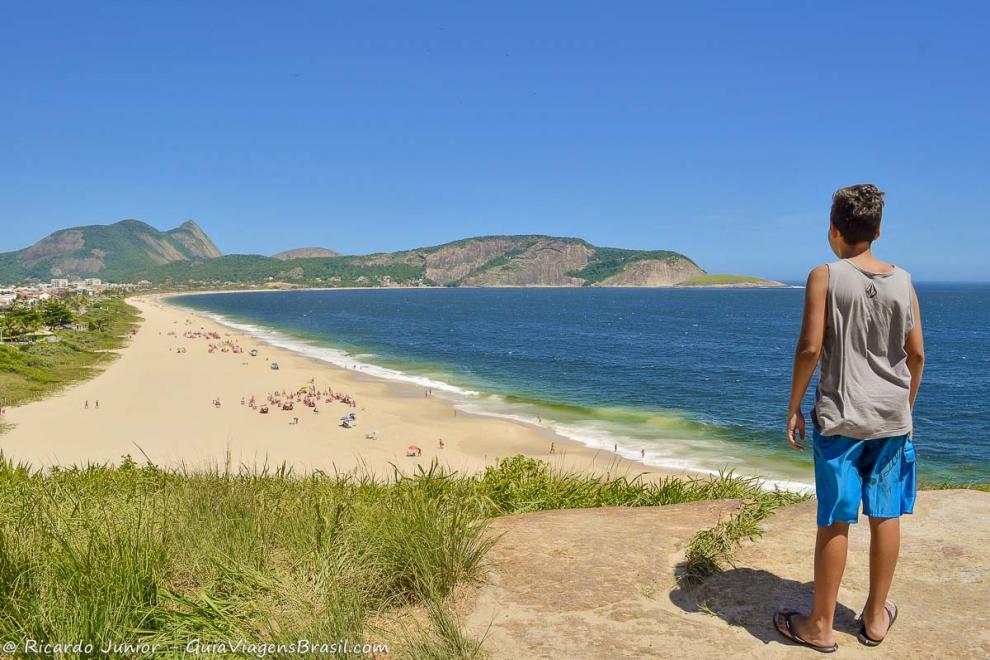 Imagem de um menino admirando a orla da Praia de Camboinhas em Niterói.